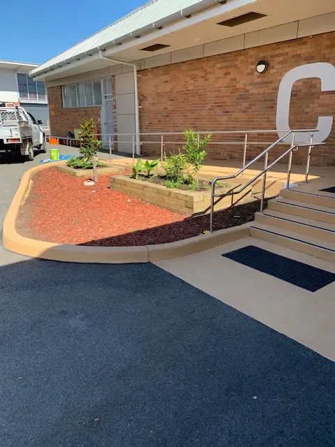 Tan sealed concrete stairs and curbing at a school building entrance