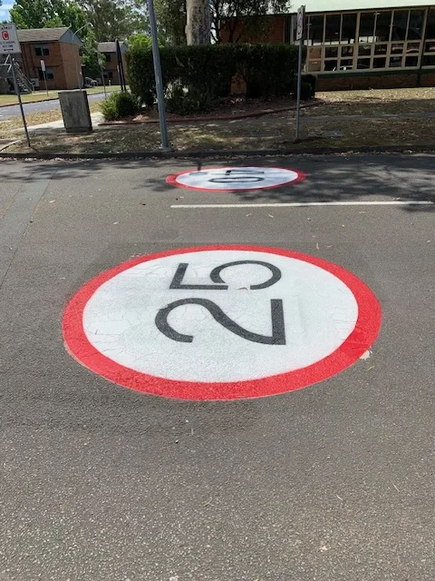 25 and 40 km/h speed limit roundels on a sealed road at a defence facility