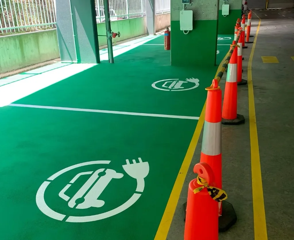 Green EV charging bays with white car and plug stencils at a Lane Cove car park