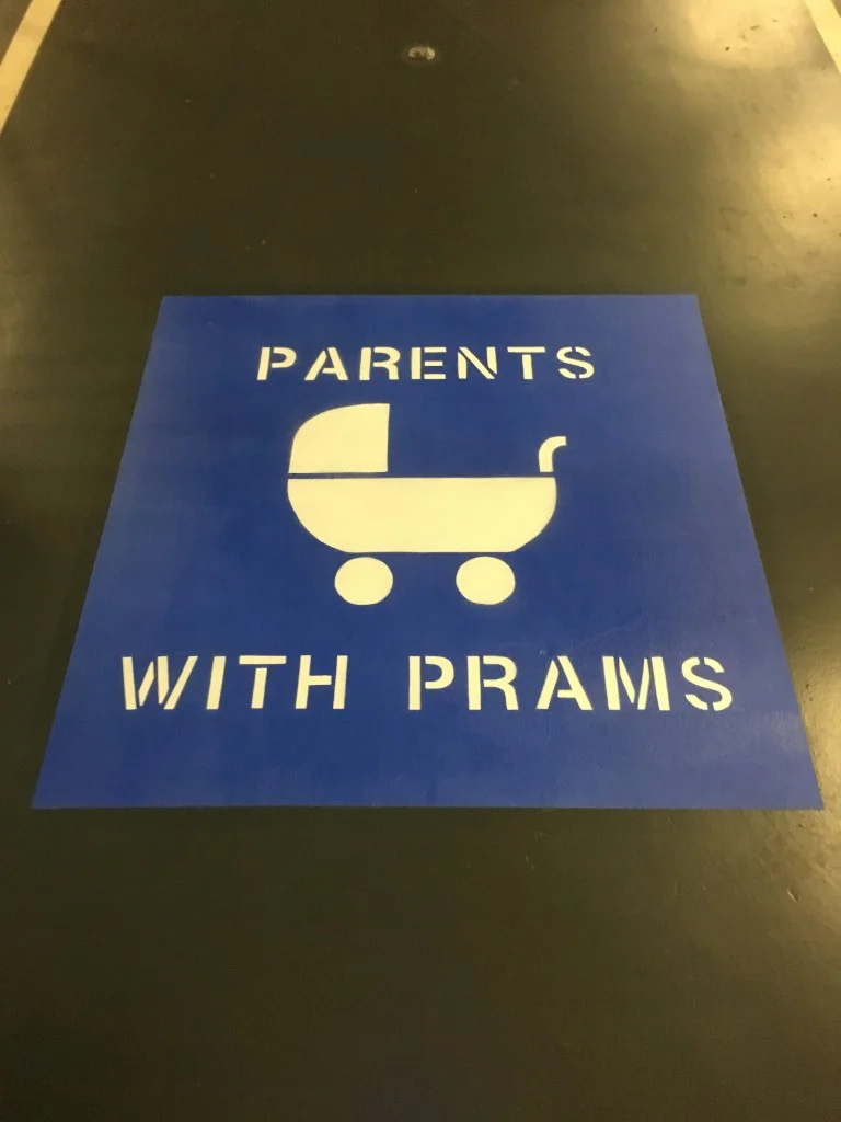 Blue parents with prams parking bay with white stencil text and pram icon