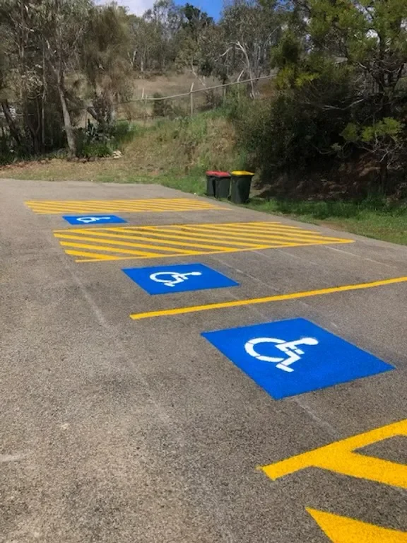 Blue disabled parking bays with yellow hatched shared zone on new asphalt