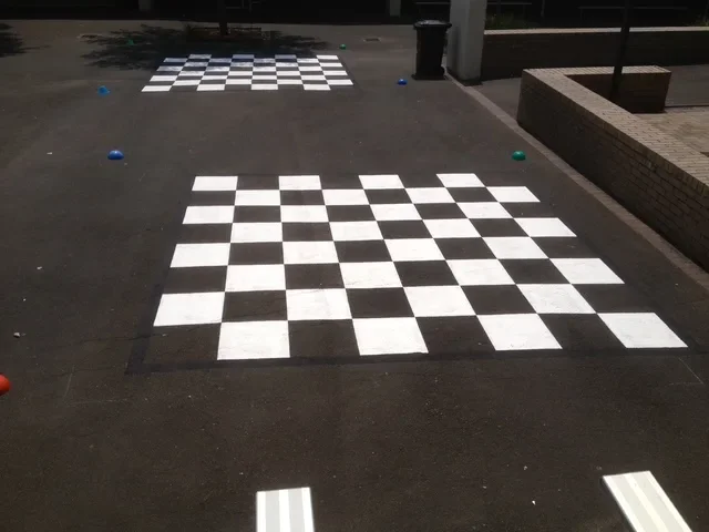 Two large black and white checkerboard grids on a school asphalt playground