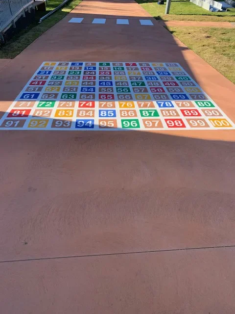 Multicolour 1 to 100 number grid painted on a school concrete walkway
