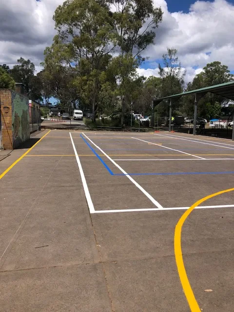 Overlapping white, yellow and blue basketball, tennis and volleyball court lines on a school concrete court in Campbelltown
