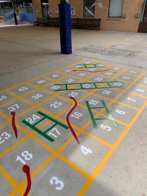 Colourful snakes and ladders playground marking with numbered yellow grid squares
