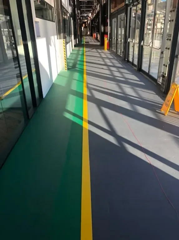 Blue and yellow pedestrian walkway markings in a warehouse corridor